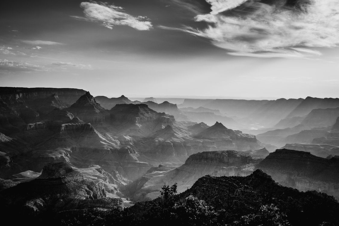 grayscale photo of mountains under cloudy sky