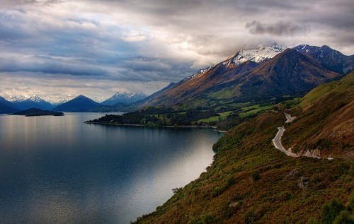 Image lake in the middle of green and brown mountains under white clouds