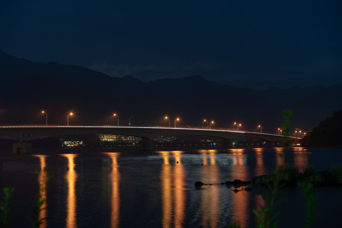 Beleuchtete Brücke Über Wasser Während Der Nacht Night. Wallpaper in 7952x5304 Resolution