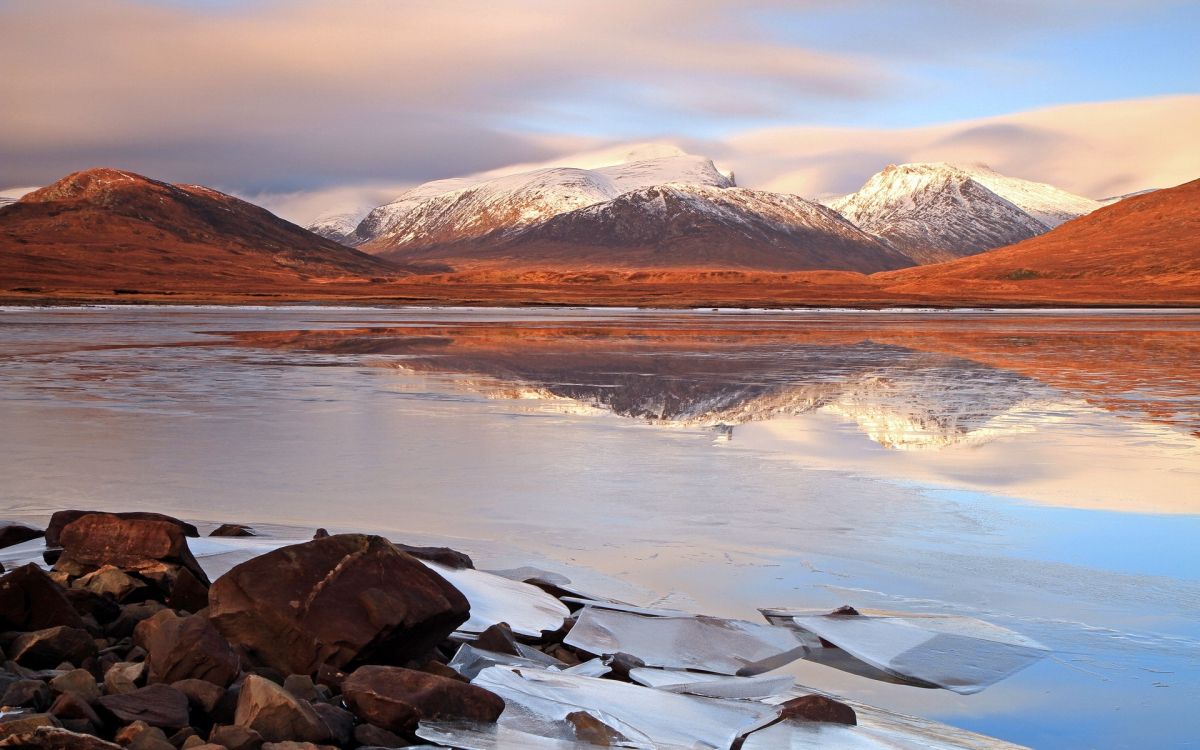 brown and white mountains near body of water during daytime