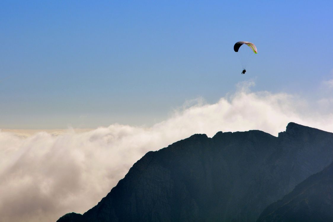 Person Riding Parachute Over Mountain. Wallpaper in 4009x2674 Resolution