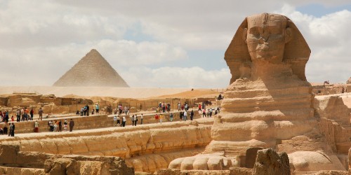 Image people walking on the street near pyramid during daytime