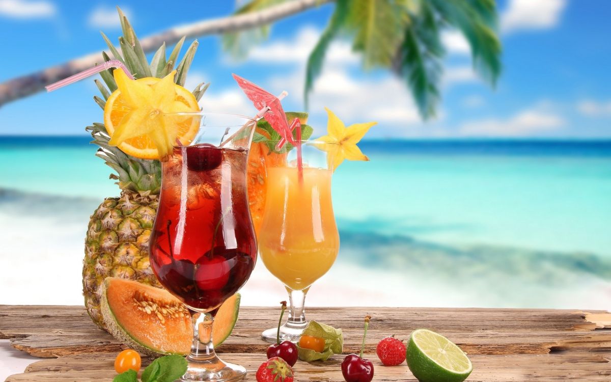 clear wine glass with red liquid and lemon on beach during daytime