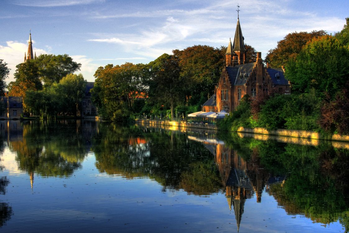 brown concrete building near green trees and body of water during daytime